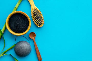 Hair care, hair spa. Cosmetics based on bamboo charcoal powder near comb on blue background top view space for text