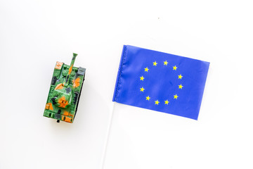 War, military threat, military power concept.European Union. Tanks toy near european flag on white background top view