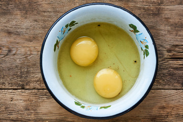 Raw chicken eggs in a metal bowl on a wooden background      