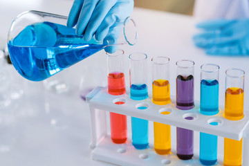 scientist with equipment and science experiments, laboratory glassware containing chemical liquid for research or analyzing a sample into test tube in laboratory