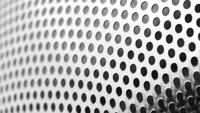 Rotated perforated steel surface background.