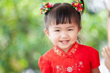 Happy cute asian little child girl in chinese tradition dress smiling  and wishing you a happy in Chinese New Year