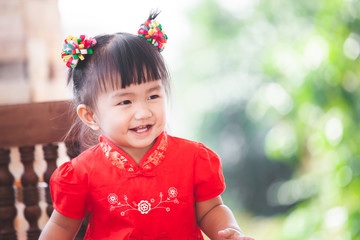 Happy cute asian little child girl in chinese tradition dress smiling  and wishing you a happy in Chinese New Year