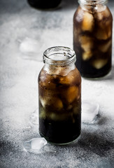 Healthy food and drink concept: cold black detox mineral water with crushed ice in glass bottles,...