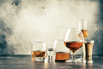 Selection of hard strong alcoholic drinks in big glasses and small shot glass in assortent: vodka, cognac, tequila, brandy and whiskey, grappa, liqueur, vermouth, tincture, rum. - obrazy, fototapety, plakaty