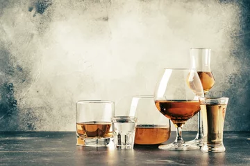 Foto op Plexiglas Selectie van harde sterke alcoholische dranken in grote glazen en kleine borrelglaasjes in assortiment: wodka, cognac, tequila, cognac en whisky, grappa, likeur, vermout, tinctuur, rum. © 5ph