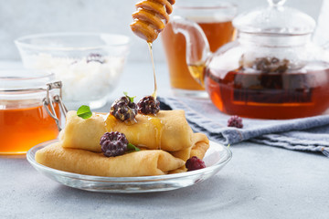 Crepes with ricotta filling served with honey and blackberries.