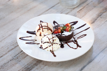 Dark chocolate fondant cake with ice cream on white plate