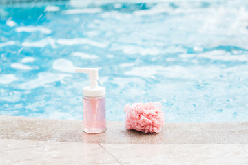 A bottle of pink shower gel and shower net sponge