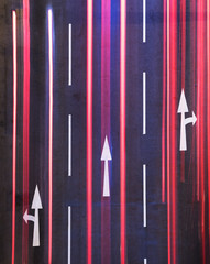Night traffic on road. White arrow sign painted on black asphalt