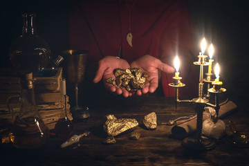 Alchemist is working at his magic table and producing a gold from a stones. - obrazy, fototapety, plakaty