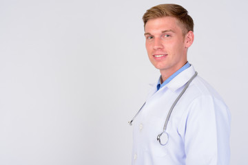 Profile view of happy young man doctor with blond hair looking at camera