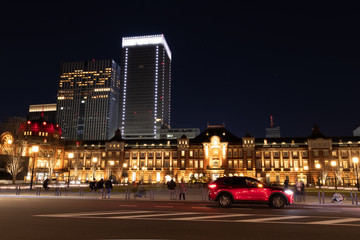 Fototapeta na wymiar ドーム屋根を赤くライトアップした東京駅と赤い車