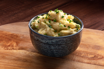 Pomme puree, a photo of a bowl of mashed potatoes with herbs on a rustic background with a place for text