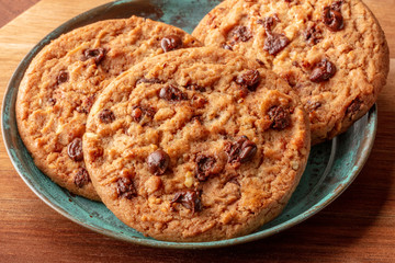 A closeup photo of chocolate chip cookies on a dark rustic wooden background