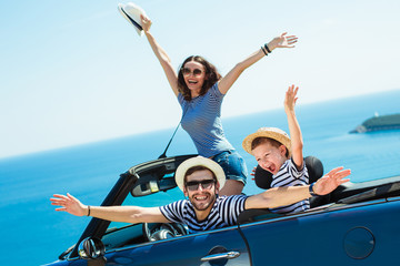 Happy family travel by car to the sea. People having fun in cabriolet. Summer vacation concept