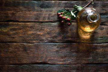 Herbal medicine essential oil and branch with berry on a table.