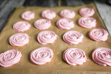 Pink raspberry meringues on a wooden background