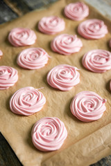 Pink raspberry meringues on a wooden background