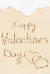 Happy Valentine's Day handwritten text on the sand beach, soft wave on background