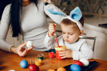 Naklejka premium Mother and son paint eggs. Family sitting in a kitchen. Preparing for Easter