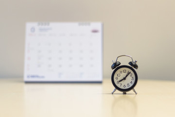 Alarm clock with calendar background - Time management concept..
