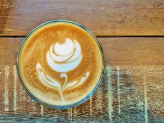 Cup of coffee on the table with latte art - Rose, top view on wooden table background.