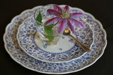 Scene of the plate of the table and a flower and the glass