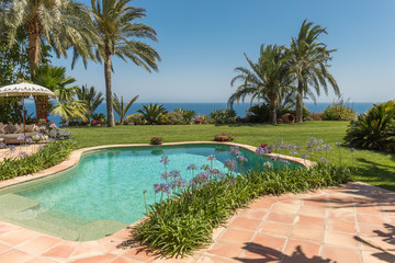 Fototapeta premium Beautiful blue swimming pool in resort or home on summer paradise with coconut trees or palm trees in the background. Holiday or holiday with sophistication and decoration with glamorous style