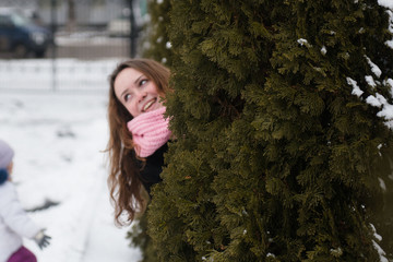 Fototapeta na wymiar Young woman posing in a black coat and pink woolen scarf in the winter in the park