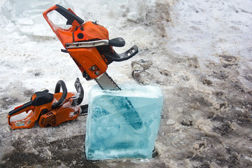 Chainsaw inserted into the ice block. Concept: cutting out figures from ice, folk art, craftsmanship, construction from ice.