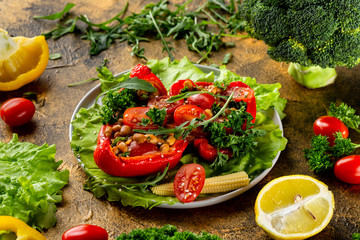 Closeup plate of fresh vegetarian salad with tomatoes, corn, beans, pepper and parsley at golden textured decorated with vegetables table background.