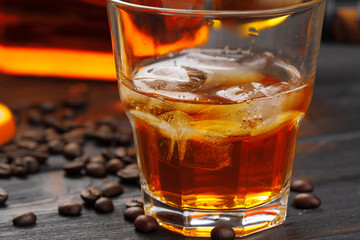 Whiskey or liqueur, coffee beans and orange cut on wooden background. Seasonal holidays concept.