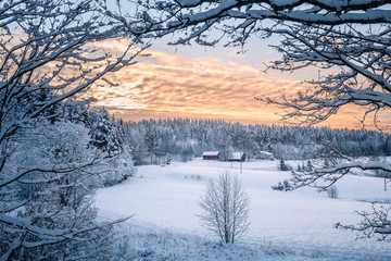 Scenic winter landscapw with farm house and sunset at evening light in Finland