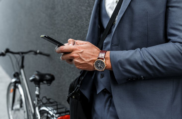 Close up of businessman hands using smartphone on the street.