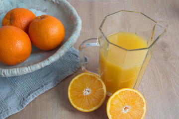 High angle view of orange juice and bowl with oranges on the table