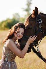 Obraz premium The bride in a delicate pink dress with paillettes on a brown horse. Wedding in the forest at sunset. Walking in the nature near the water.