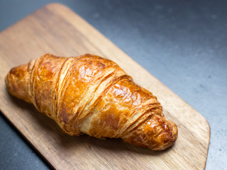 Fresh croissant on wooden board on a black background