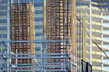 Concrete pillars on construction site. Building of skyscraper with crane, tools and reinforced steel bars