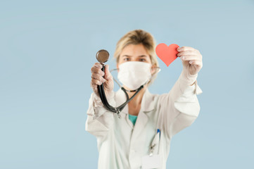 beautiful girl doctor with a red heart in her hands on a blue isolated background.Concept of love