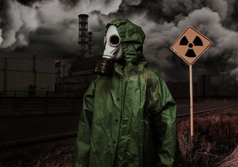 Man in gas mask and cloak of chemical protection on abandoned road.
