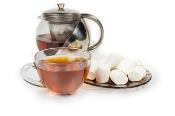 Black tea in cup and teapot, marshmallow on saucer