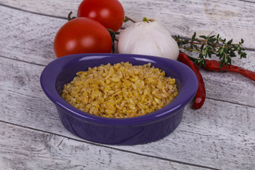 Raw bulgur in the bowl with tomatoes and garlic