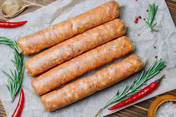 Raw Tyrolean sausages with rosemary over wooden background
