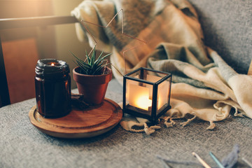 Home decoration Nordic interior details and Cosy place on grey sofa by the warm pompon blanket and cushions vase and candle on the wooden tray