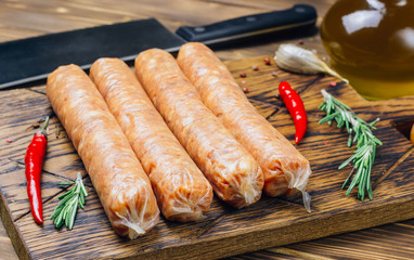Raw Tyrolean sausages with rosemary over wooden background