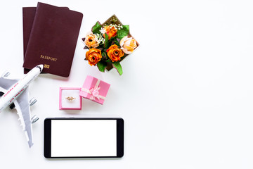 Mock up image of mobile smart phone with blank white screen, diamond ring in gift box,two passports and plane isolated on white.clipping path.Honey moon trip concept. 