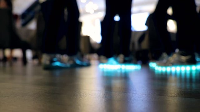 Blurred background or texture, of glowing and flashing shoes on the feet of the girls, light blue