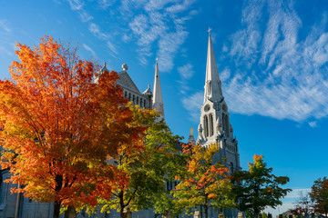 Fototapeta premium Exterior view of the Basilica of Sainte-Anne-de-Beaupre church with red maple tree