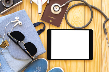 Trip,travel and insurance concept. Mock up image of black digital tablet with blank white screen,passport,medical stethoscope and plane model on white background. Clipping path and copy space.